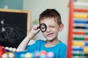 Schoolboy looking through a magnifying glass